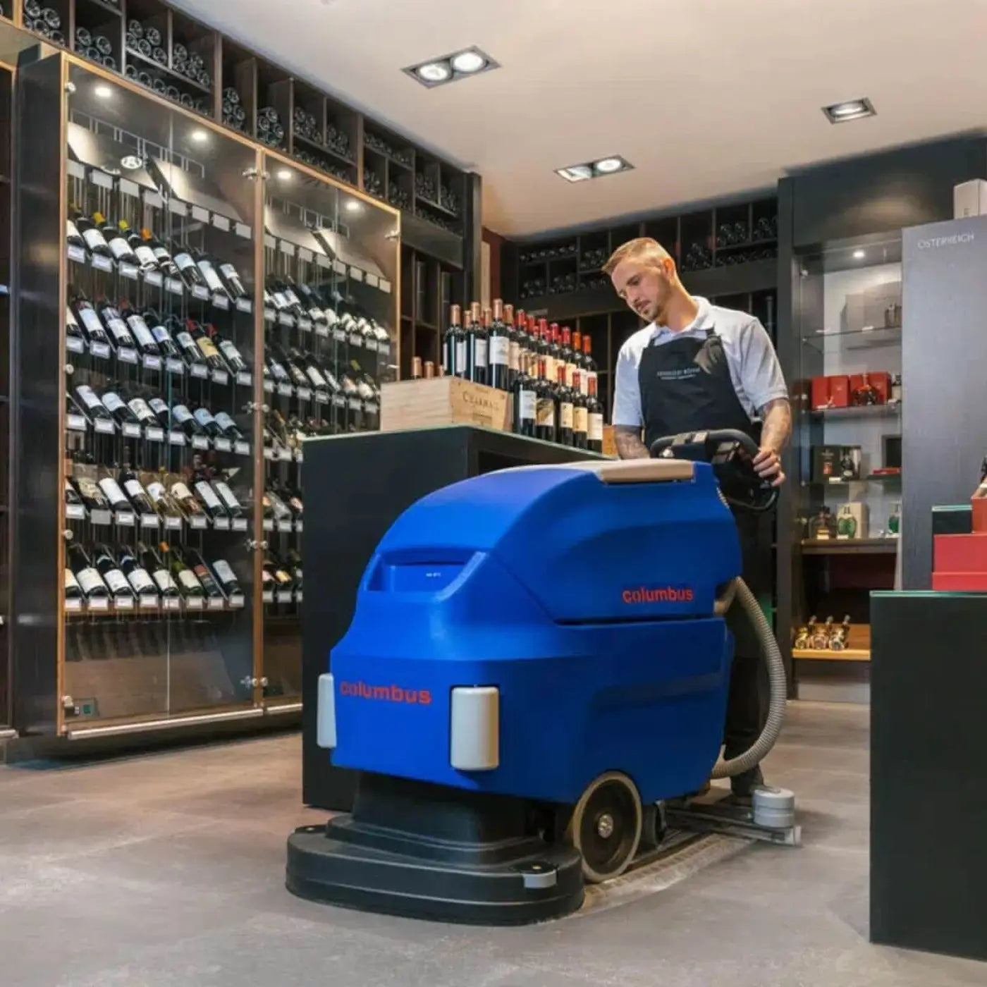 Blue columbus ra 66 bm 60 scheuersaugmaschine mit schwarzen rädern und grauen schläuchen von hinten gezeigt