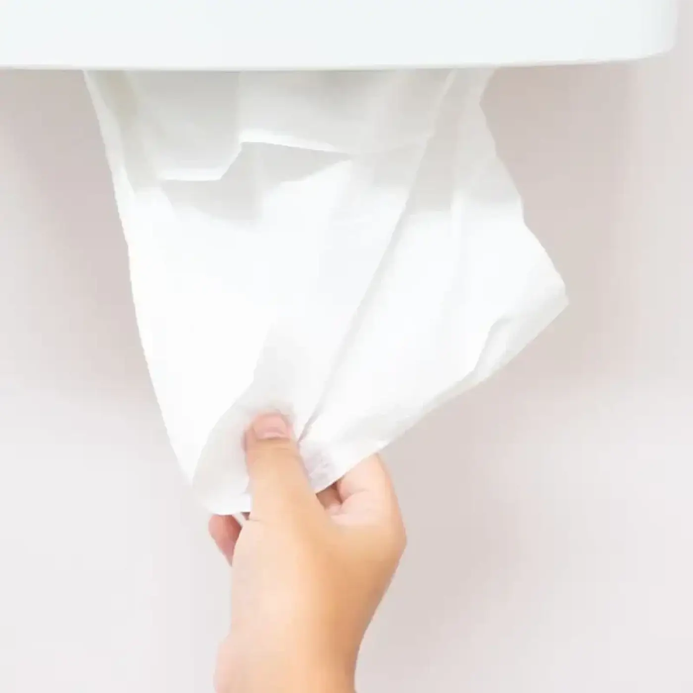 Ein weiches weißes hygoclean papierhandtuch aus 2-lagigem fsc-recyclingpapier wird aus einem spender gezogen