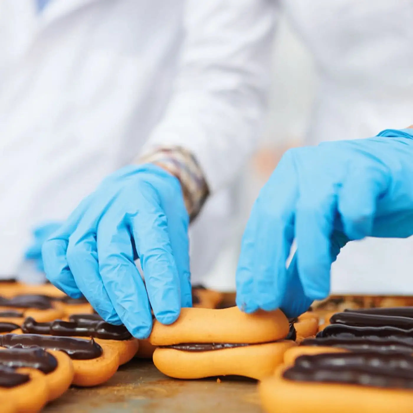 Blaue nitril handschuhe hygostar safe premium werden verwendet, um goldbraune schokoladen gefüllte backwaren zu handhaben