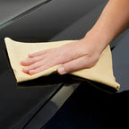 Beige mikrofasertuch zur autopflege verwendet zum polieren einer glänzenden schwarzen oberfläche mit sonax autoshampoo konzentrat 2l