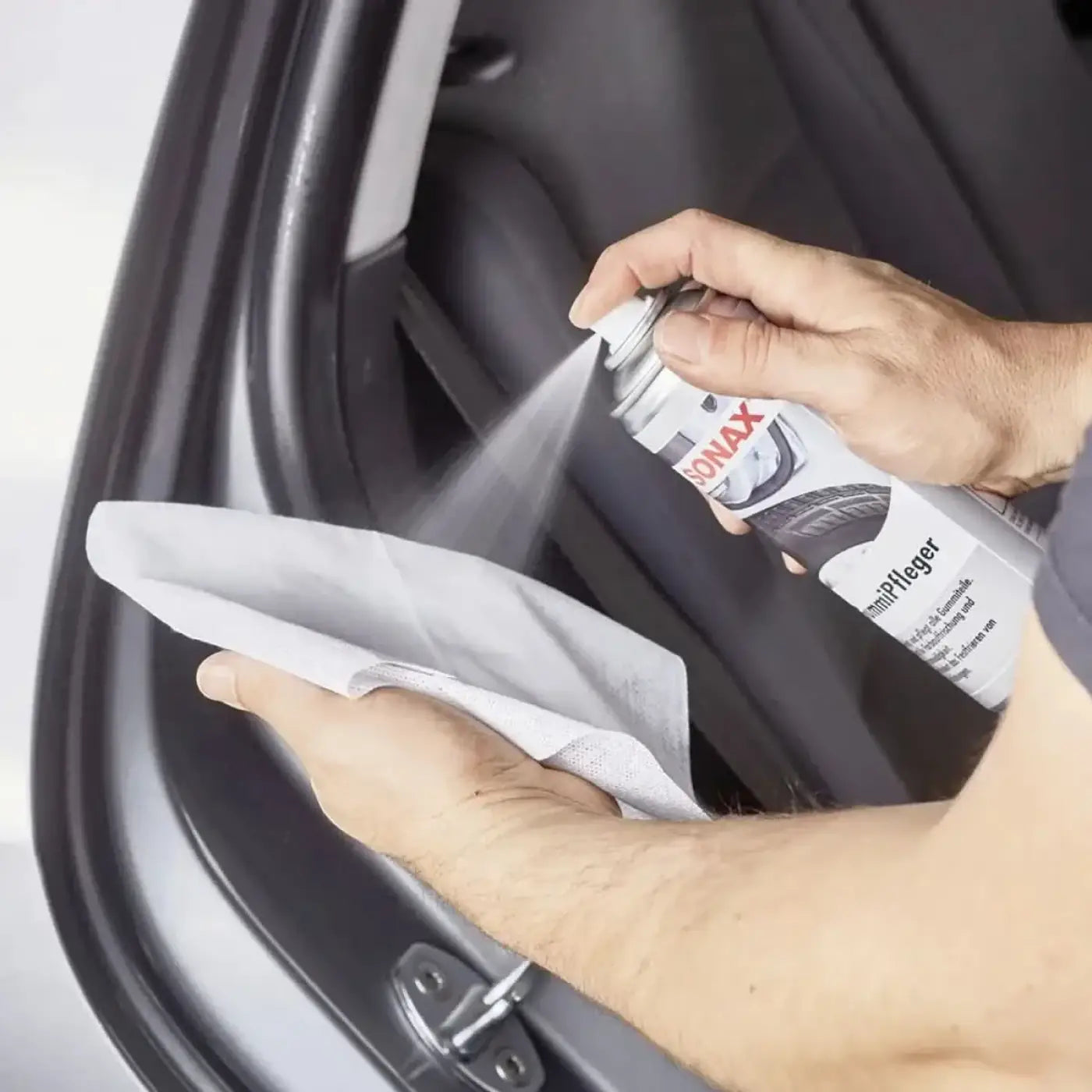 Ein silber-schwarzes aerosol von sonax gummipfleger wird in eine fahrzeugtür gesprüht zur pflege aller gummiteile