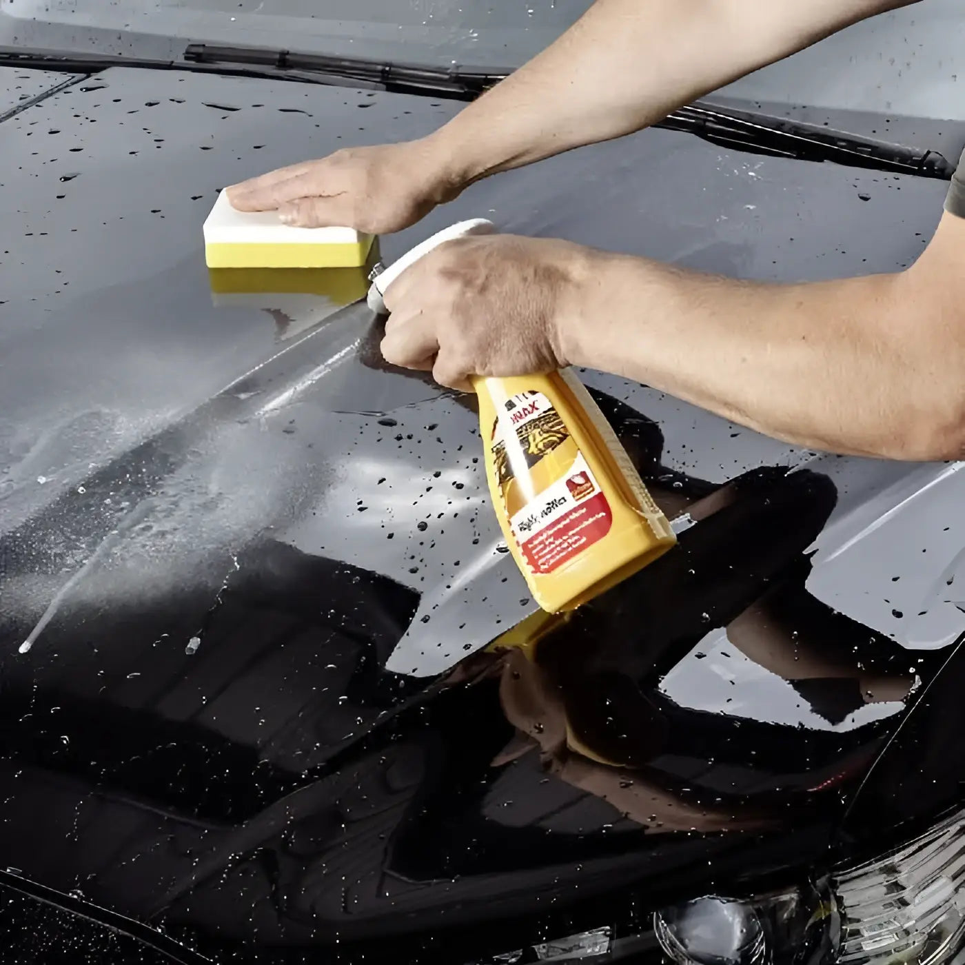 Gelbe flasche meguiars wax-it-on autowachs wird auf die motorhaube eines schwarzen fahrzeugs aufgetragen