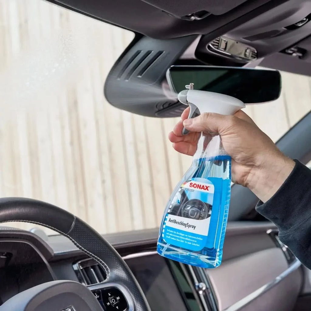 Ein transparenter blauer sprayflasche mit weißem abzug und etikett sonax antibeschlagspray für autoinnenverglasung