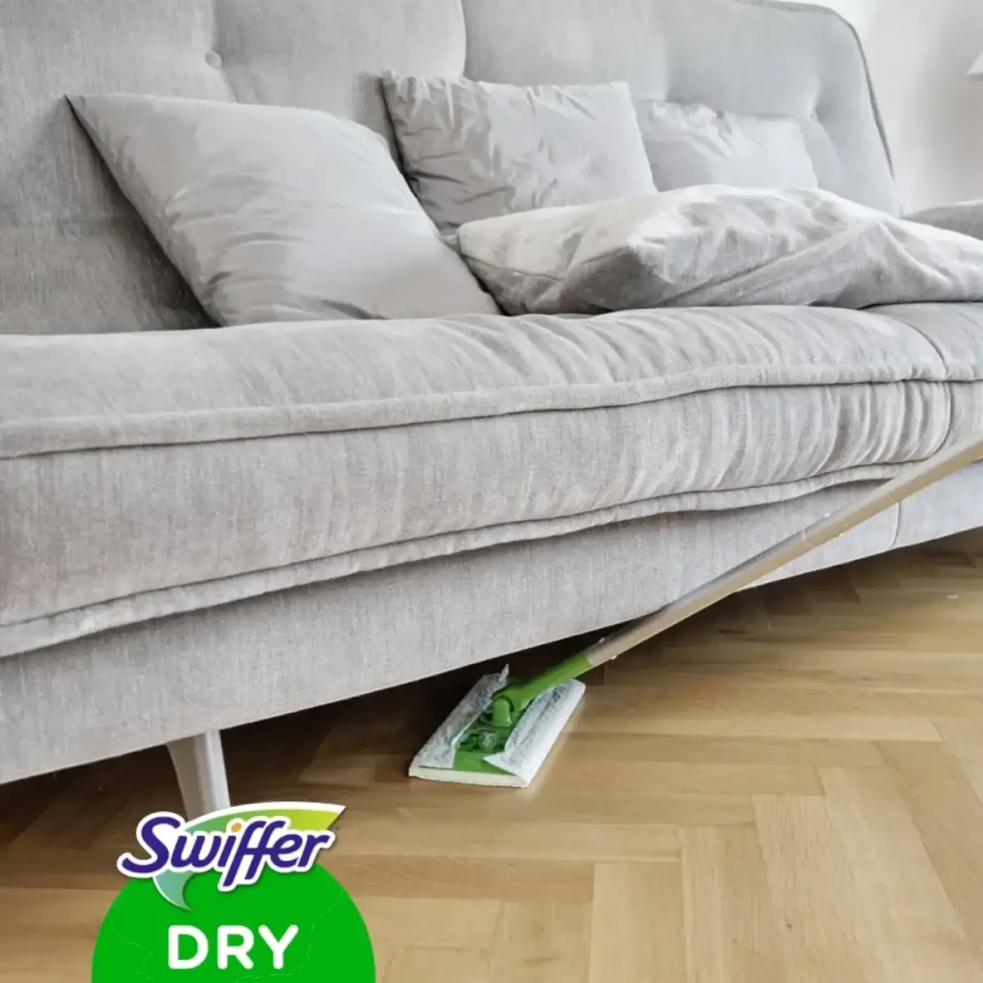 Swiffer anti-staub tücher trocken in grün und weiß auf holzboden unter grauem sofa liegend