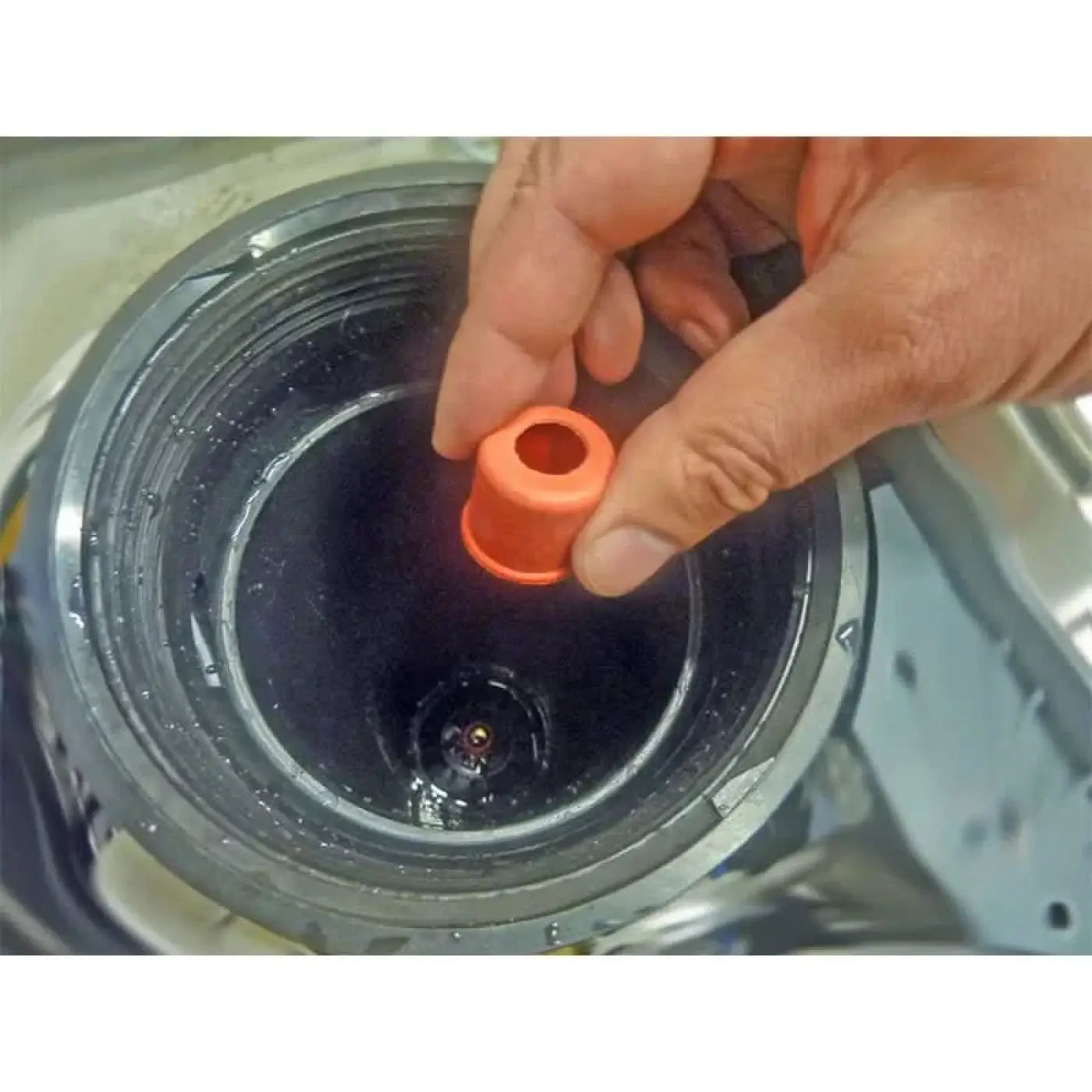 Orange gummidichtung aus dem unger hydropower ro dichtungsringe set wird über eine dunkle runde öffnung gehalten