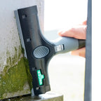 Black and gray unger Kunststoffklingen squeegee with textured grip handle used to remove green moss from surface