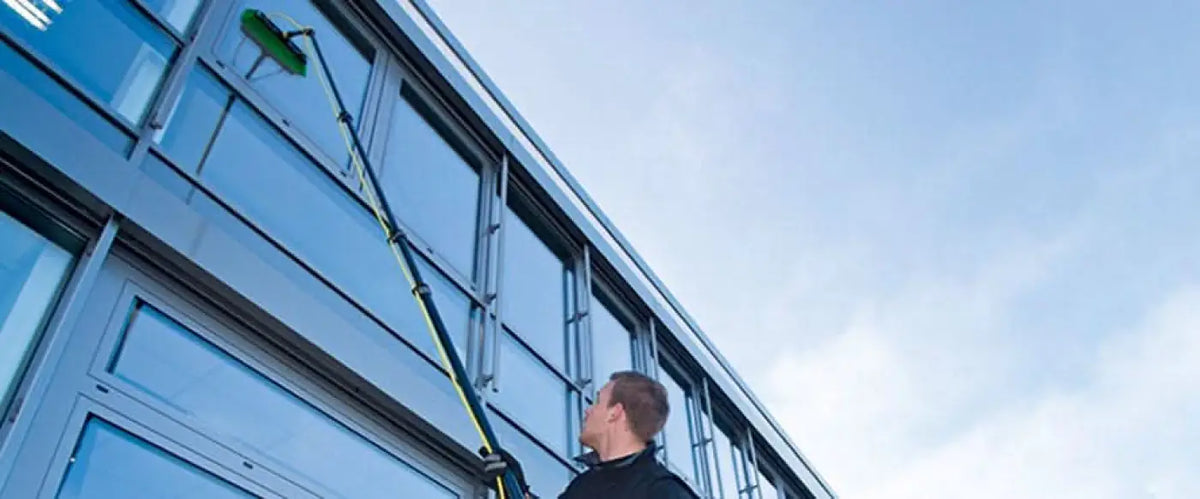 Ein mann verwendet die grüne und schwarze ungere nlite connect ultra himod karbon erweiterungsstange zum reinigen von fenstern