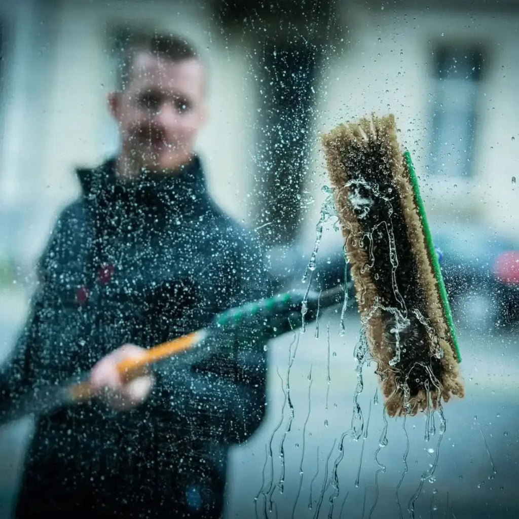 Unger nlite hybrid bürste nuh braune borsten mit grünem griff tropft wasser beim reinigen von glas